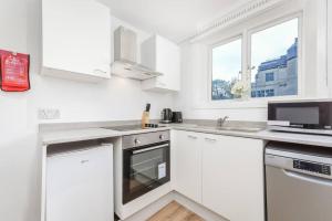 a white kitchen with white cabinets and a window at 2 Bed Piccadilly Apartment- 4 in London