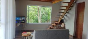 un salon avec un escalier et une fenêtre dans l'établissement Estrela da Montanha 2, à Santo Antônio do Pinhal