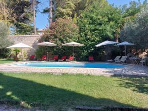 a swimming pool with umbrellas and chairs and tables at Mas Fontclaire - Sommières in Sommières