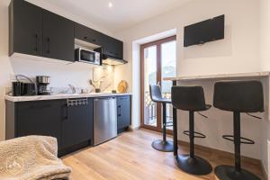a kitchen with black cabinets and two bar stools at ALPINA LODGE VANOISE ex hotel du soleil in Aussois