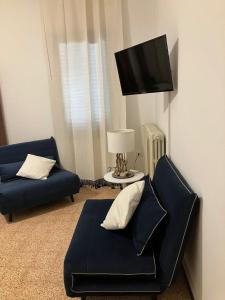 - un salon avec deux canapés bleus et une télévision à écran plat dans l'établissement La casa delle Querce, à San Pietro in Vincoli