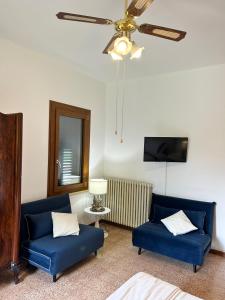 a living room with two blue couches and a ceiling fan at La casa delle Querce in San Pietro in Vincoli