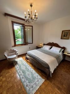 a bedroom with a bed and a chair and a chandelier at La casa delle Querce in San Pietro in Vincoli