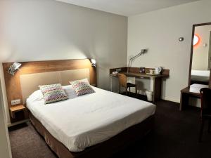 a hotel room with a bed and a desk at Campanile Belfort Montbéliard - Gare La Jonxion. in Meroux