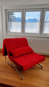 un banco rojo en una habitación con 2 ventanas en Appartement Twin Peak Edelweiss, en Gosau