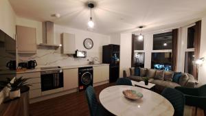 AT Evita Suites في كارديف: مطبخ وغرفة معيشة مع طاولة وأريكة