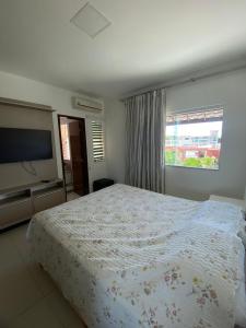 een slaapkamer met een groot bed en een televisie bij Casa Recanto de Guarajuba in Camassari