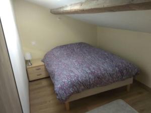 ein kleines Schlafzimmer mit einem lila Bett im Dachgeschoss in der Unterkunft Le gîte du Grangeon Bugiste à Argis 