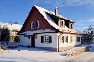 une maison avec un toit rouge dans la neige dans l'établissement Landluft Ferien - Wohnung Abendrot, à Heiligenberg