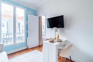 Zimmer mit einem weißen Schreibtisch und einem TV an der Wand in der Unterkunft Flat next to Montparnasse train station in Paris