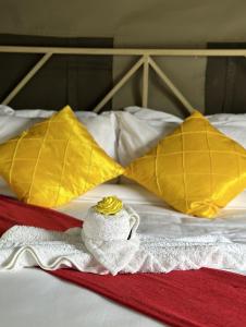 uma cama com duas almofadas amarelas e uma toalha em SABI Escapes em Mochudi