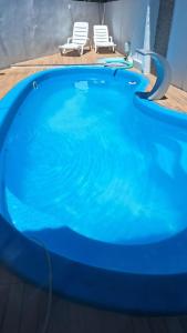 una gran piscina azul con 2 sillas blancas en Paraíso da Deise en Mata de Sao Joao