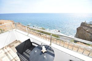 een tafel en stoelen op een balkon met uitzicht op de oceaan bij House with view sound of waves in Paránimfoi