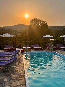 a pool with chairs and a sunset in the background at Pensiunea PORTAS RESORT in Slănic