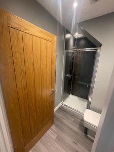 a bathroom with a wooden door and a shower at An Bothan in Mallaig