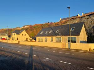 a house on the side of a road next to a hill at An Bothan in Mallaig