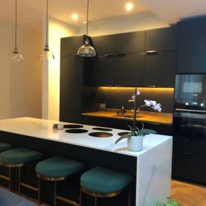 a kitchen with a counter with a stove and stools at Stunning Modern Large 5 Bed House Willesden in London