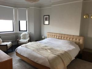 a bedroom with a bed and a chair and windows at Stunning Modern Large 5 Bed House Willesden in London