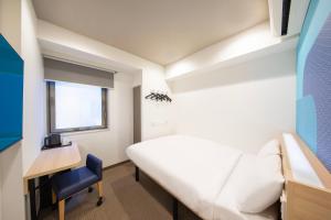 um quarto com uma cama, uma secretária e uma janela em Hop Inn Tokyo Iidabashi em Tóquio