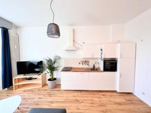 a kitchen with white cabinets and a tv in it at Central apartment in trendy Friedrichshain in Berlin