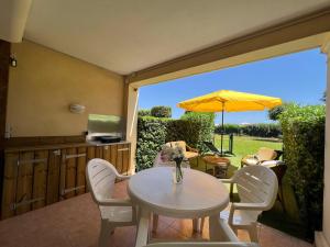 eine Terrasse mit einem Tisch, Stühlen und einem Sonnenschirm in der Unterkunft Appartement au Hameau des Issambres Le Pamakior in Les Issambres