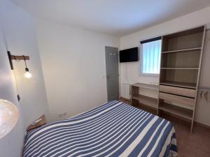 ein kleines Schlafzimmer mit einem blau-weißen gestreiften Bett in der Unterkunft Appartement au Hameau des Issambres Le Pamakior in Les Issambres