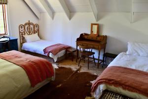 1 dormitorio con 2 camas, escritorio y piano en Bamboo Mountain Farm en Underberg