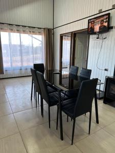 a dining room with a table and chairs and a television at Complejo Turístico Los Laureles Arauco in Arauco