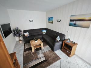 een woonkamer met een zwarte bank en een tafel bij Ferienwohnung Hidde in Ostseebad Koserow