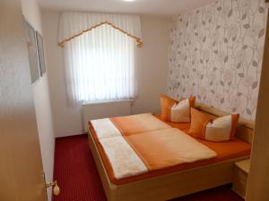 een slaapkamer met een bed met oranje lakens en een raam bij Ferienwohnung Hidde in Ostseebad Koserow