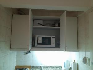 a kitchen with white cabinets with a microwave at GÜEMES in Mar del Plata