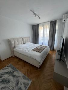 a white bedroom with a large bed and a television at Arena Mila in Novi Beograd