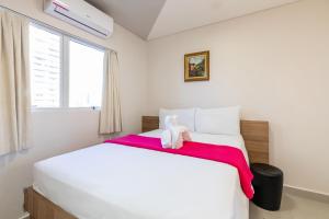 um quarto com uma grande cama branca e um cobertor vermelho em Tarobá Express em Foz do Iguaçu