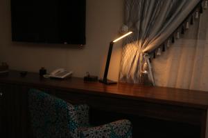 a desk in a hotel room with a lamp and a chair at Saire Hotels Ibadan in Ibadan