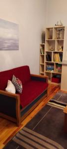 sala de estar con sofá rojo y estante para libros en Like your home en Komotini