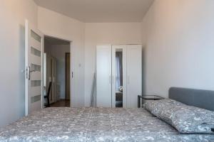 a white bedroom with a bed and a mirror at Apartament Zajezdnia Wrzeszcz Gdańsk 1 in Gdańsk