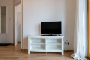 una TV seduta su un supporto bianco in una stanza di Apartament Zajezdnia Wrzeszcz Gdańsk 1 a Danzica