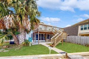 a house with a wooden staircase in a yard at Palm Getaway in Panama City Beach