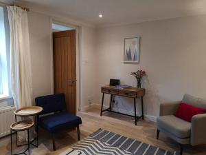 a living room with chairs and a table and a desk at Owl's Hoot in Snettisham