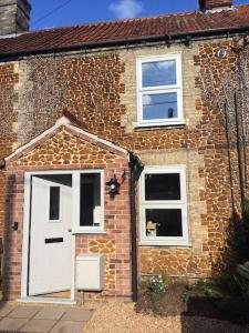 a brick house with a white door and two windows at Owl's Hoot in Snettisham