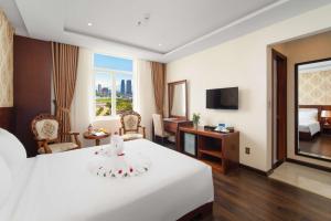 a hotel room with a large white bed and a desk at NATURE Hotel By K D H in Da Nang