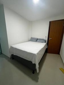 a bed in a white room with a wooden door at Village 3/4 a 140m da praia in Ilhéus