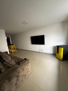Il comprend un salon doté d'un canapé et d'une télévision à écran plat. dans l'établissement Village 3/4 a 140m da praia, à Ilhéus