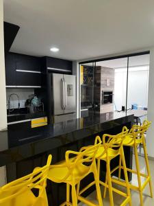 a kitchen with yellow chairs and a yellow table at Village 3/4 a 140m da praia in Ilhéus