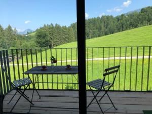 a table and chairs on a porch with a view of a field at Apartment Stillleben Luxus für die Seele in Abtenau