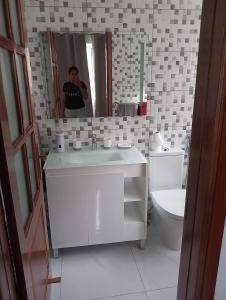 um homem tirando uma foto de uma casa de banho com um lavatório e WC em Bentub home em Ribeira Grande