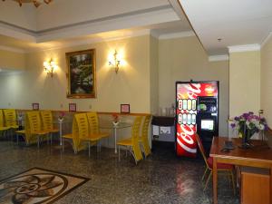 a restaurant with a soda machine and tables and yellow chairs at Flushing Hotel in Queens