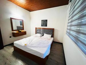 1 dormitorio con 1 cama con sábanas blancas y ventana en Nature Bliss Villa, en Aluthgama
