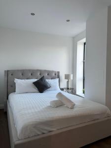 uma cama branca com duas almofadas em cima em Spacious 2BR with balcony in Brentwood em Brentwood