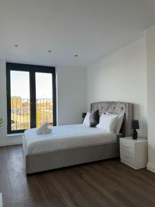 a white bedroom with a large bed and a window at Spacious 2BR with balcony in Brentwood in Brentwood
